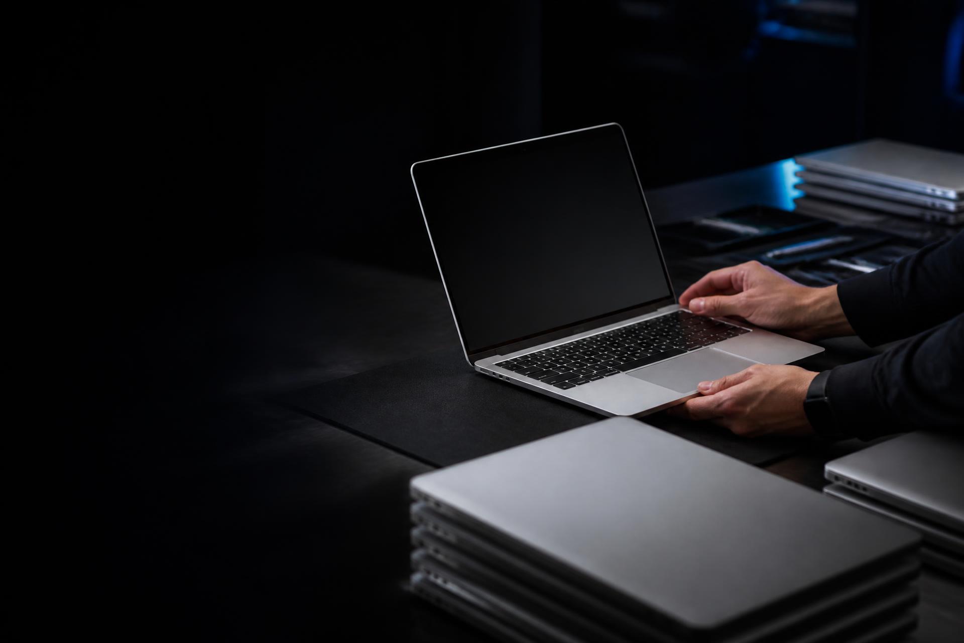 Silver MacBook laptops being inspected and prepared for enterprise servicing